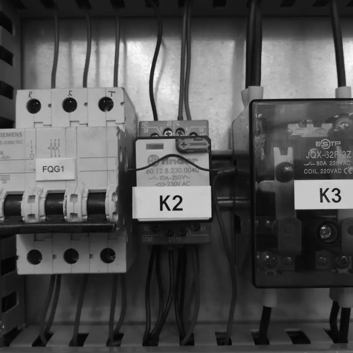 Riel de control dentro del gabinete: interruptor termomagnético trifásico, contactor de potencia y relevador auxiliar, cada uno con su etiqueta de identificación.