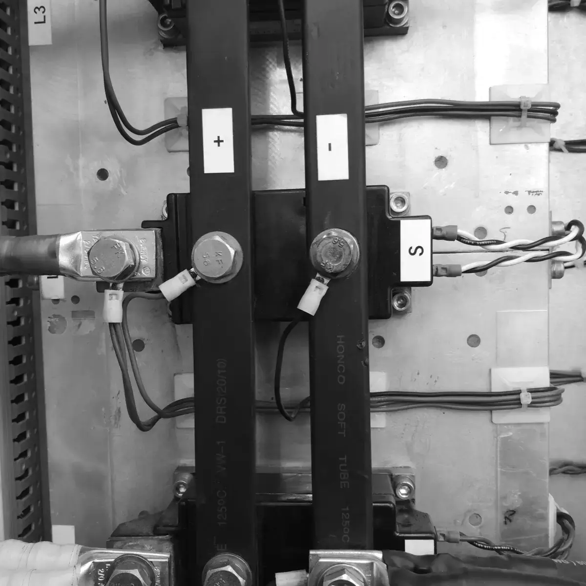 Barras de salida de corriente directa, marcadas + y −, atornilladas a los módulos de potencia y conectadas con cable calibrado al proceso.